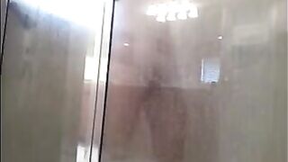 A man washes himself in the shower, unaware of being filmed