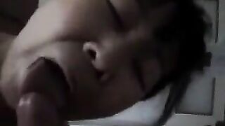 An adult Chinese woman practices her blowjob skills on her man in bed