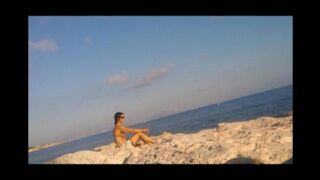 A naked girl is basking in sunbaths on the beach