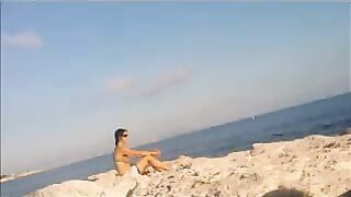A naked girl is basking in sunbaths on the beach
