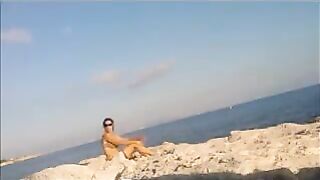 A naked girl is basking in sunbaths on the beach