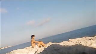A naked girl is basking in sunbaths on the beach